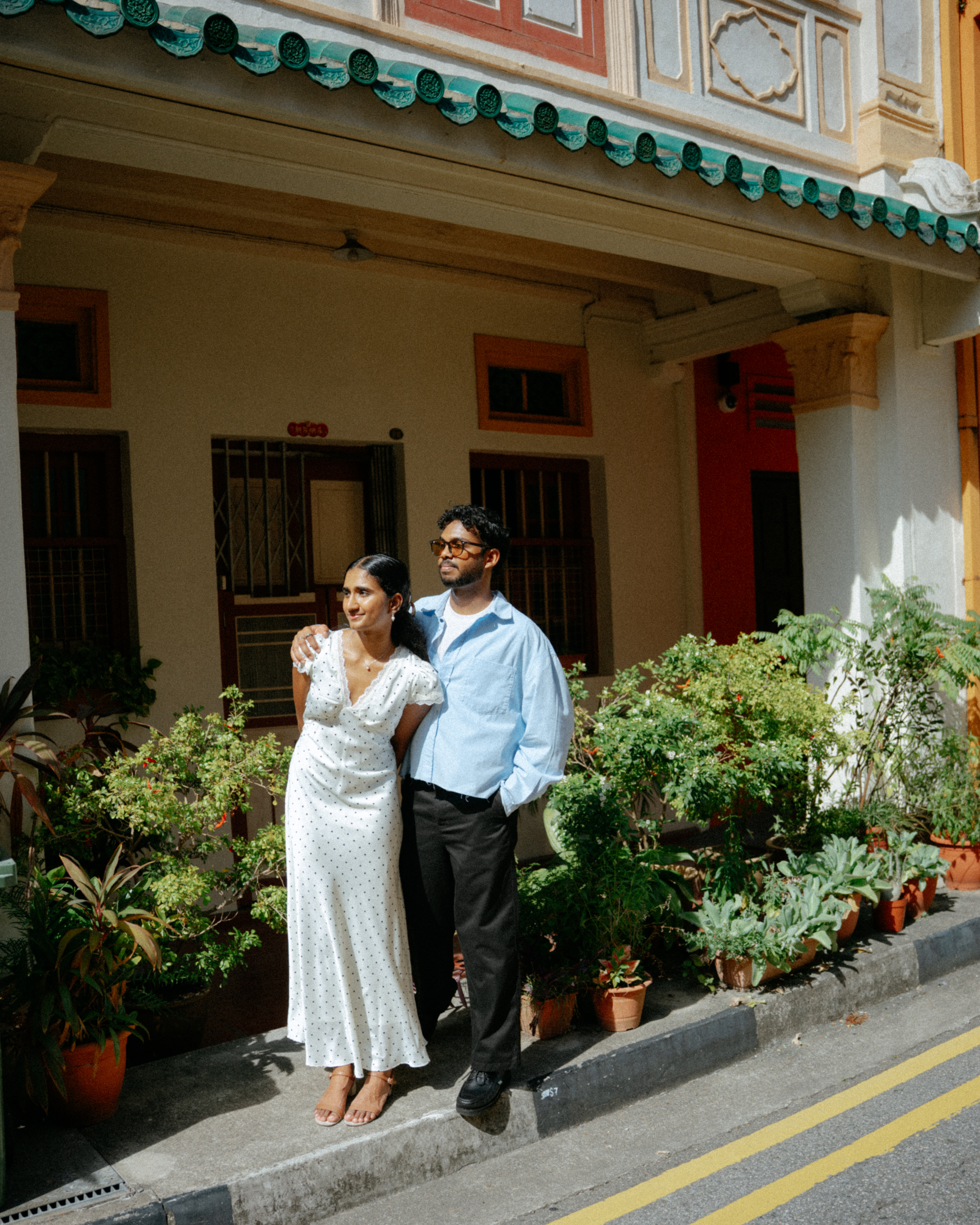 Janani and Dhanush standing together near heritage architecture