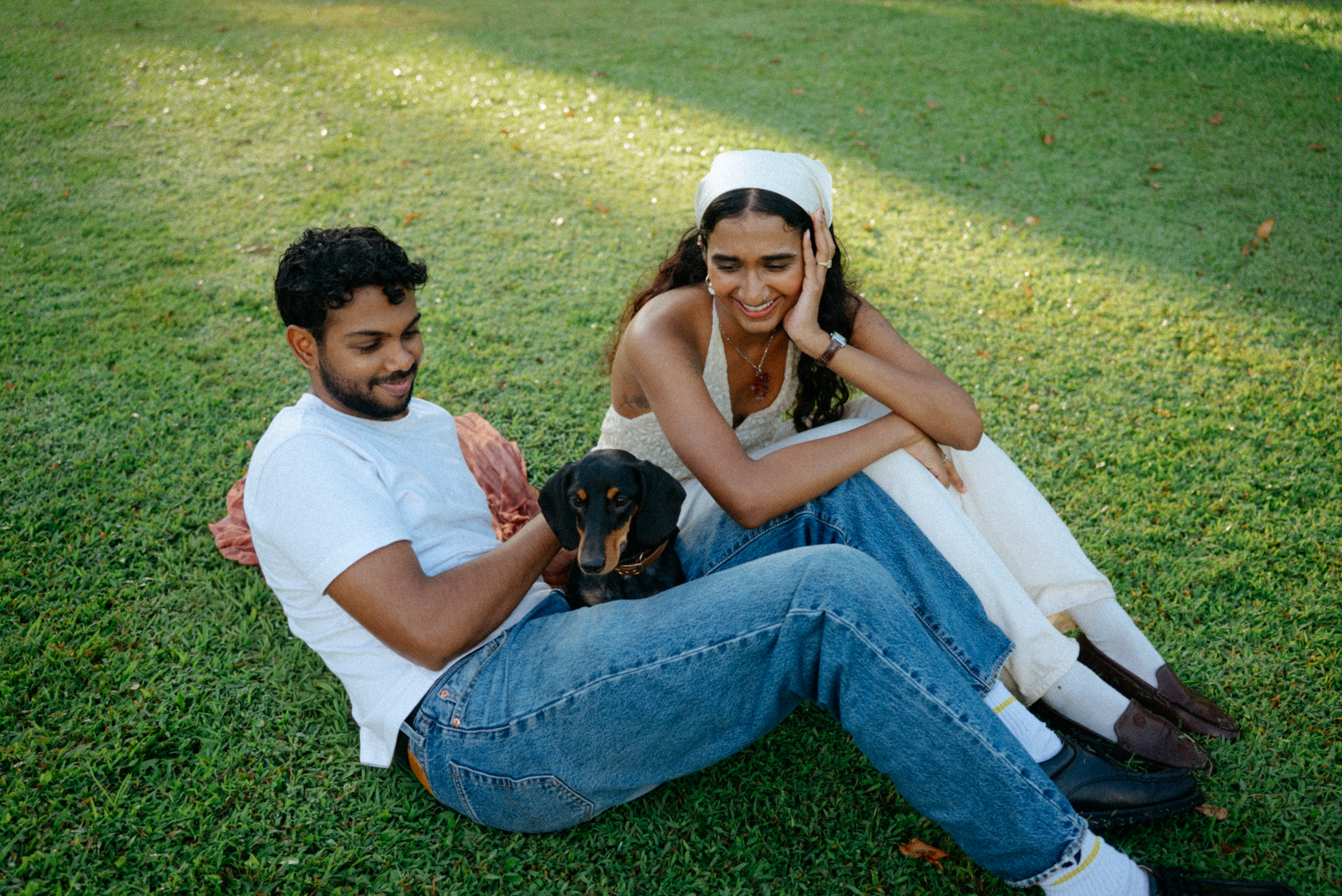 Janani and Dhanush seated together on grass with their dog